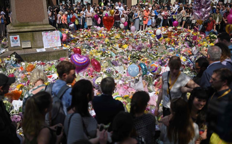 People stop by a mass of flowers to observe a minute's silence in St Ann's Square in Manchester on May 25, 2017 (AFP via Getty Images)