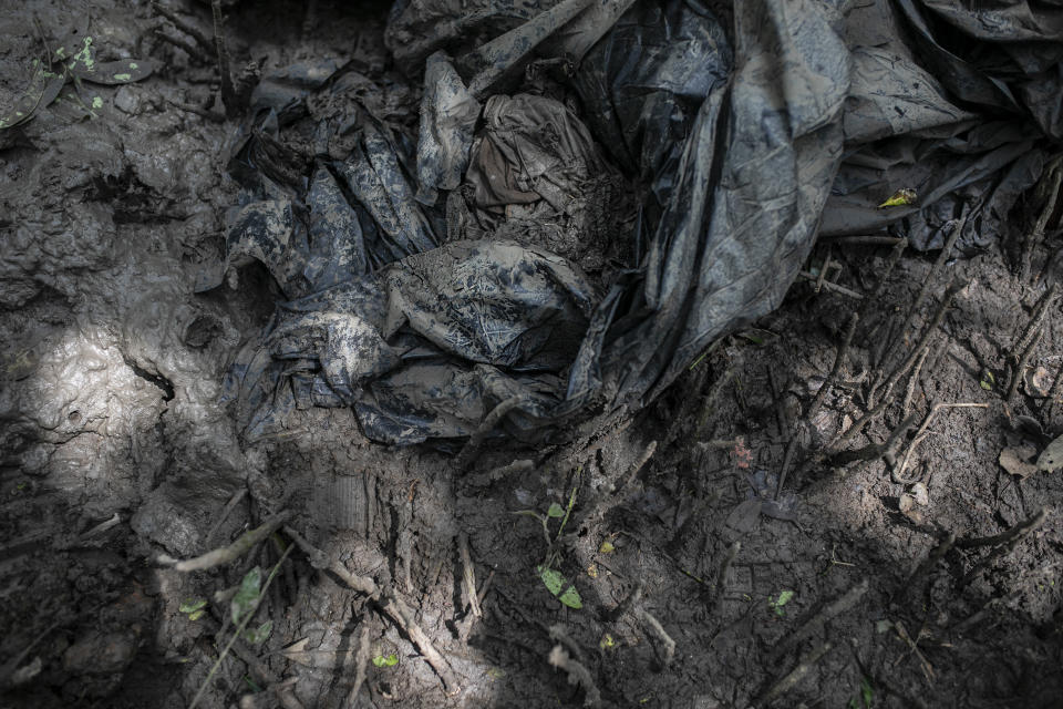 Clothes and black plastic bags lay on the ground at a clandestine grave site in Puquita, a tropical mangrove island near Alvarado in the Gulf coast state of Veracruz, Mexico, Thursday, Feb. 18, 2021. Investigators from the National Search Commission found three pits with human remains and plastic bags inside. The number of bodies there has not yet been determined. (AP Photo/Felix Marquez)