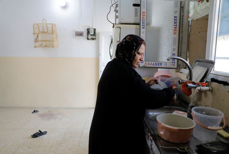 Rasha Saeed washes dishes at her rented house in the old city of Mosul