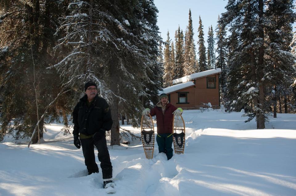 Danny Cresswell, left, and Niko Helm of the Carcross/Tagish First Nation snowshoe near a cabin near Little Atlin Lake in early 2023. The First Nation argued the cabin was unlawful, and the Yukon government has since ordered that it be dismantled.
