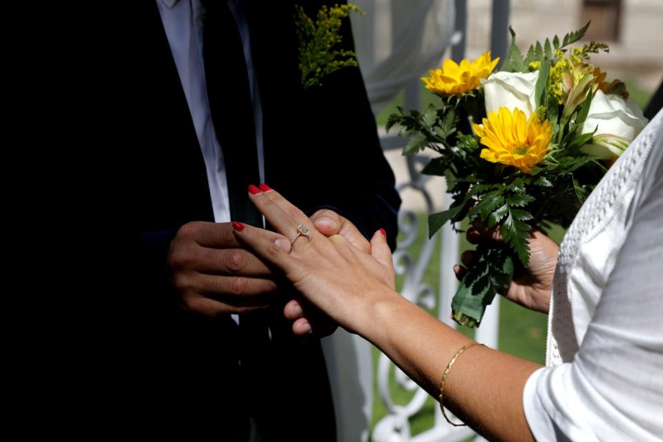 Enrique Alvarez, left, slides a wedding ring on the finger of Afrouz Alvarez. Feb. 22 is Alvarez's birthday.