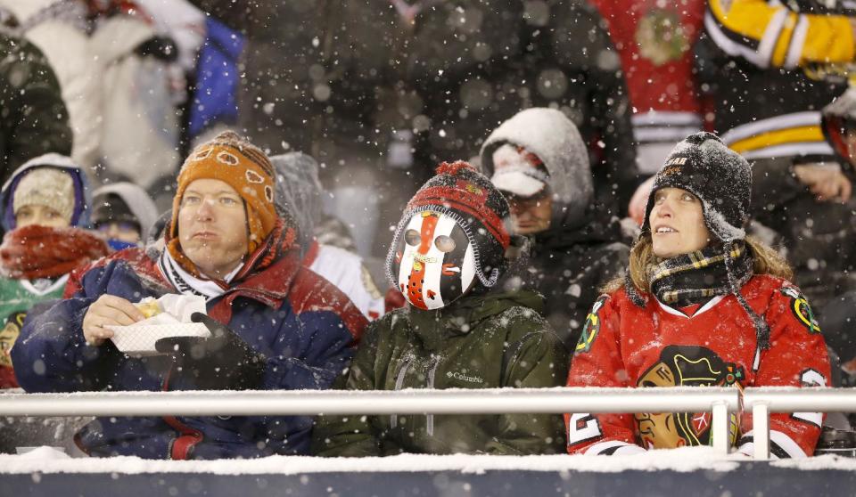 Hockey fans watch the Chicago Blackhawks face the Pittsburgh Penguins as snow falls during the first period of an NHL Stadium Series hockey game at Soldier Field on Saturday, March 1, 2014, in Chicago. (AP Photo/Charles Rex Arbogast)