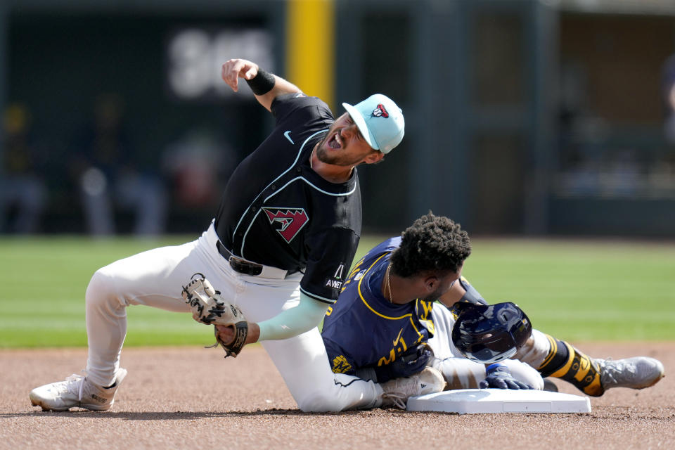 Arizona Diamondbacks second baseman Blaze Alexander, left, grimaces as Milwaukee Brewers' Jackson Chourio, right, slides into him at second base with a double during the first inning of a spring training baseball game, Sunday, March 3, 2024, in Scottsdale, Ariz. (AP Photo/Ross D. Franklin)