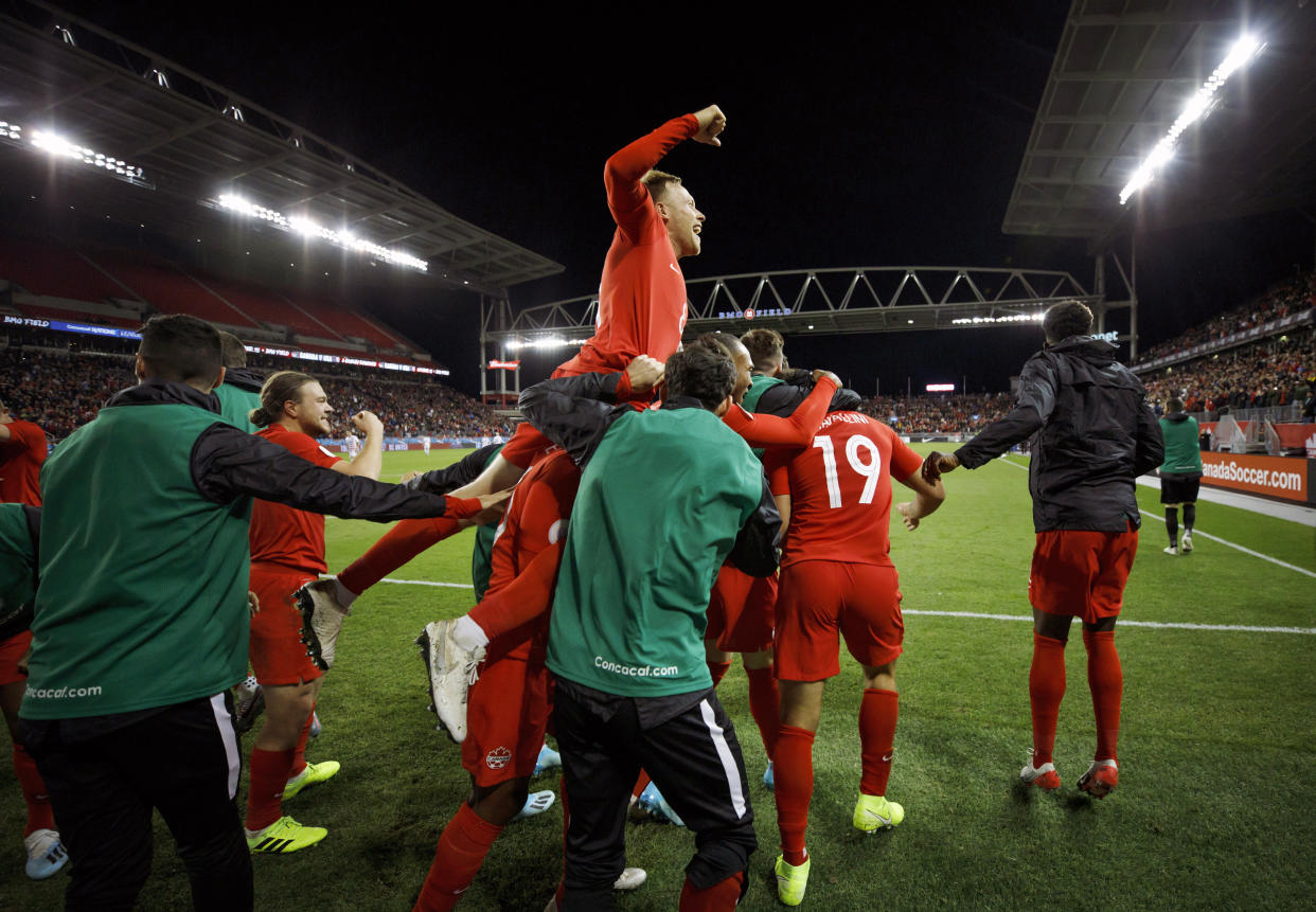 Scott Artfield, (arriba), volante de Canadá, festeja con sus compañeros un tanto de Lucas Cavallini (19), en un partido de la Liga de Naciones de la Concacaf ante Estados Unidos, el martes 15 de octubre de 2019 en Toronto (Cole Burston/The Canadian Press via AP)