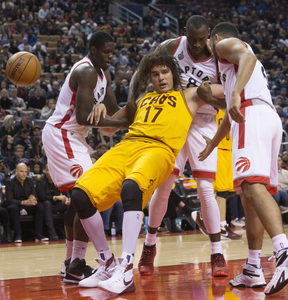 FILE - Cleveland Cavaliers' Anderson Varejao (17) is propped up by, from left to right, Toronto Raptors' Anthony Bennett, Bismark Biyombo and Cory Joseph after being fouled during first-half preseason NBA basketball game action in Toronto, Sunday, Oct. 18, 2015. Varejão has bounced back to the Cavaliers. One of the most popular players in Cleveland’s history, Varejão has been hired as a player development consultant and global ambassador for the team that he played with for 14 NBA seasons. (Chris Young/The Canadian Press via AP, File)