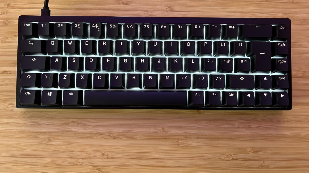  Endgame Gear KB65HE with RGB lighting on sitting on a wooden desk. 