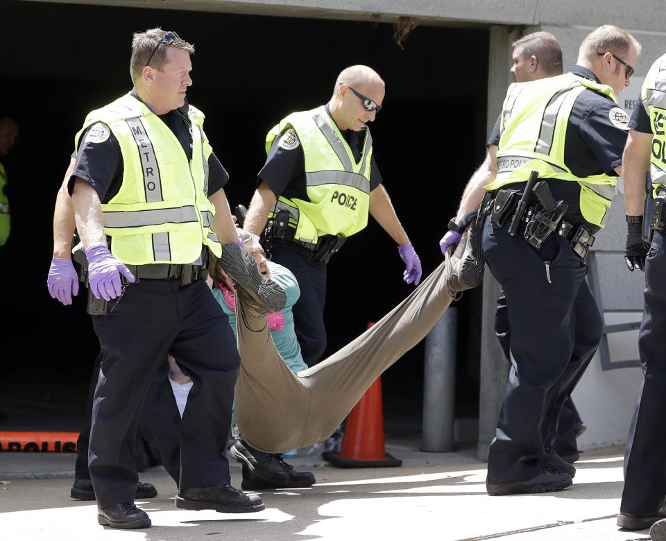 Police remove a demonstrator from outside the headquarters of CoreCivic, Monday, Aug. 6, 2018, in Nashville, Tenn. The Tennessee-based company is one of the nation's largest private prison operators and also runs eight immigration detention centers for Immigration and Customs Enforcement. (AP Photo/Mark Humphrey)