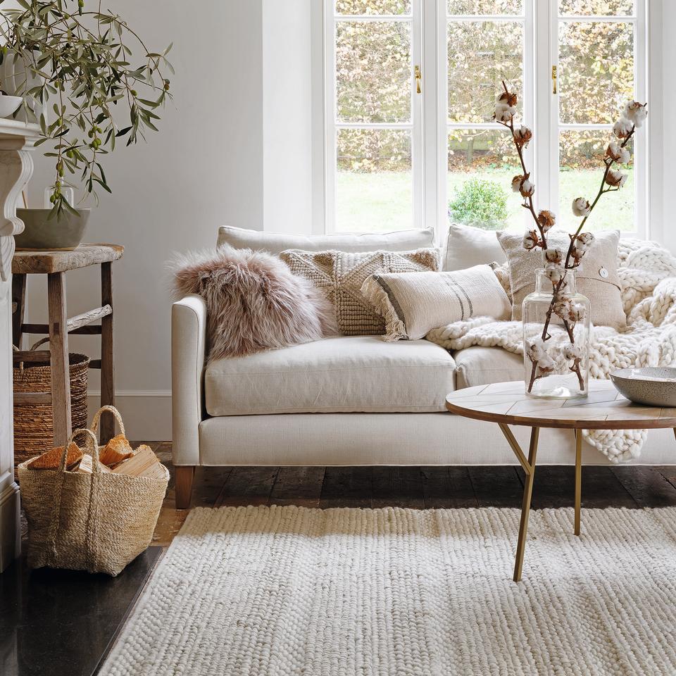 Living room with cream wool rug and cream sofa.