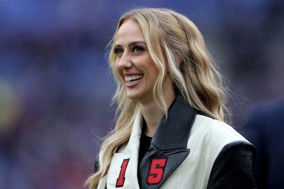 Brittany smiling wearing a jacket with '15' on it at an outdoor event