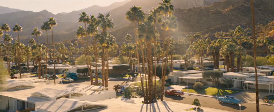 A wide shot of a town surrounded by mountains and with palm trees lining the streets