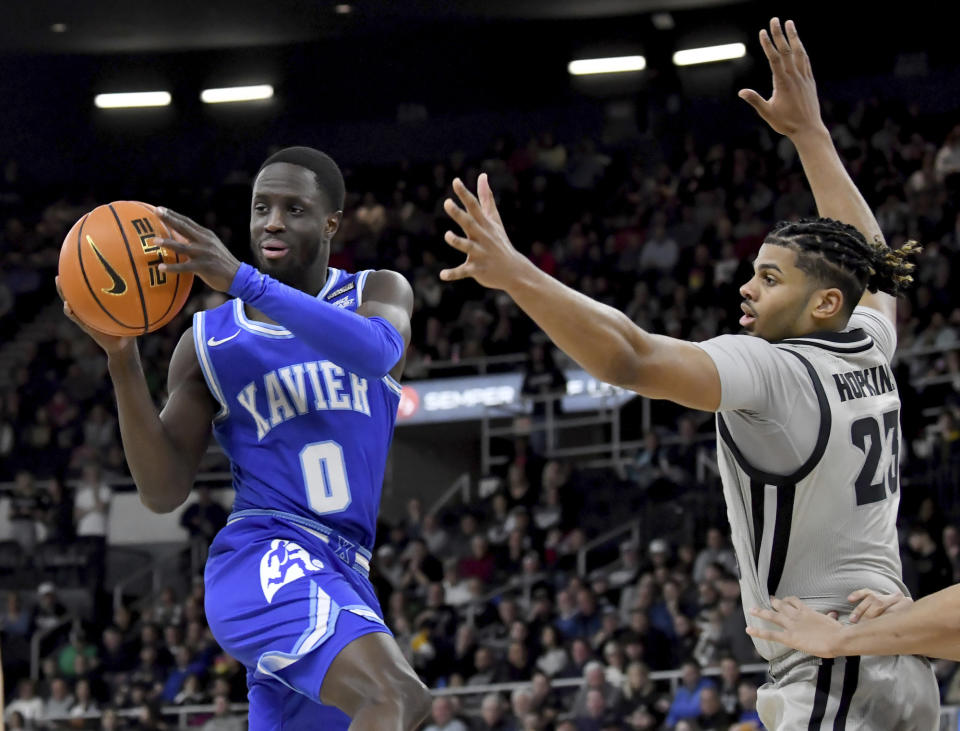 Xavier guard Souley Boum (0) passes the ball next to Providence forward Bryce Hopkins (23) during the first half of an NCAA college basketball game Wednesday, March 1, 2023, in Providence, R.I. (AP Photo/Mark Stockwell)