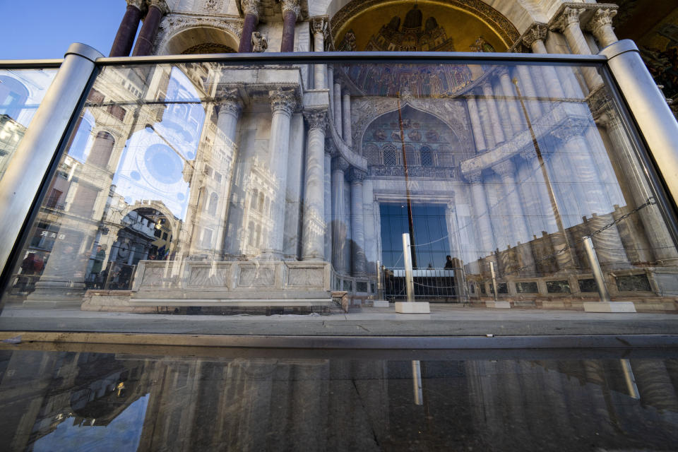 A thin layer of seawater surfaces during a moderately high tide in St. Mark's Square in Venice, northern Italy, Wednesday, Dec. 7, 2022, where glass barriers that prevent seawater from flooding the 900-year-old iconic St Mark's Basilica, partially seen in the background, have been recently installed. St. Mark's Square is the lowest-laying city area and frequently ends up underwater during extreme weather. (AP Photo/Domenico Stinellis)
