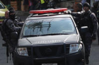 Police officers hang on to a car during an operation after clashes with drug dealers in Vidigal slum in Rio de Janeiro, Brazil August 14, 2018. Picture taken August 14, 2018. REUTERS/Ricardo Moraes