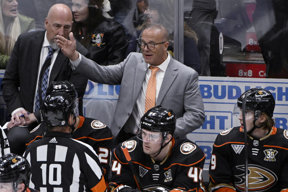 Anaheim Ducks coach Greg Cronin, center, talks with official Kyle Rehman (10) during the third period of the team's NHL hockey game against the Dallas Stars in Anaheim, Calif., Friday, March 8, 2024. (AP Photo/Alex Gallardo)