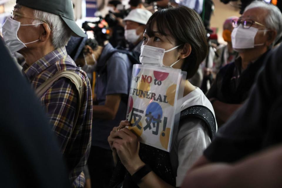 <div class="inline-image__caption"><p>A woman holds a placard during a protest against Shinzo Abe's State Funeral in front of Shinjuku Station on September 26, 2022 in Tokyo, Japan.</p></div> <div class="inline-image__credit">Takashi Aoyama/Getty</div>