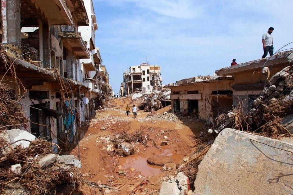 Dos personas caminan en medio de los escombros y destrozos que han dejado las inundaciones. 