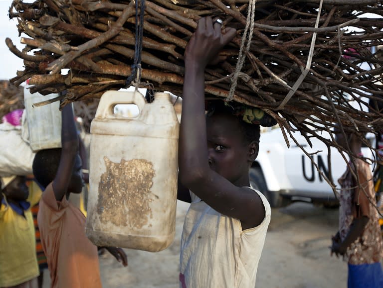 A young woman carries firewood after returning to the United Nations base outside Bentiu