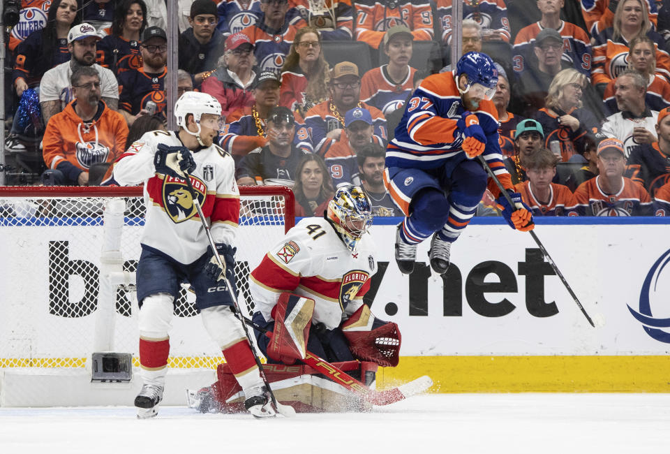 Florida Panthers goalie Anthony Stolarz (41) makes a save as Edmonton Oilers' Warren Foegele (37) leaps and Gustav Forsling (42) defends during the third period of Game 4 of the NHL hockey Stanley Cup Final, Saturday, June 15, 2024, in Edmonton, Alberta. (Jason Franson/The Canadian Press via AP)