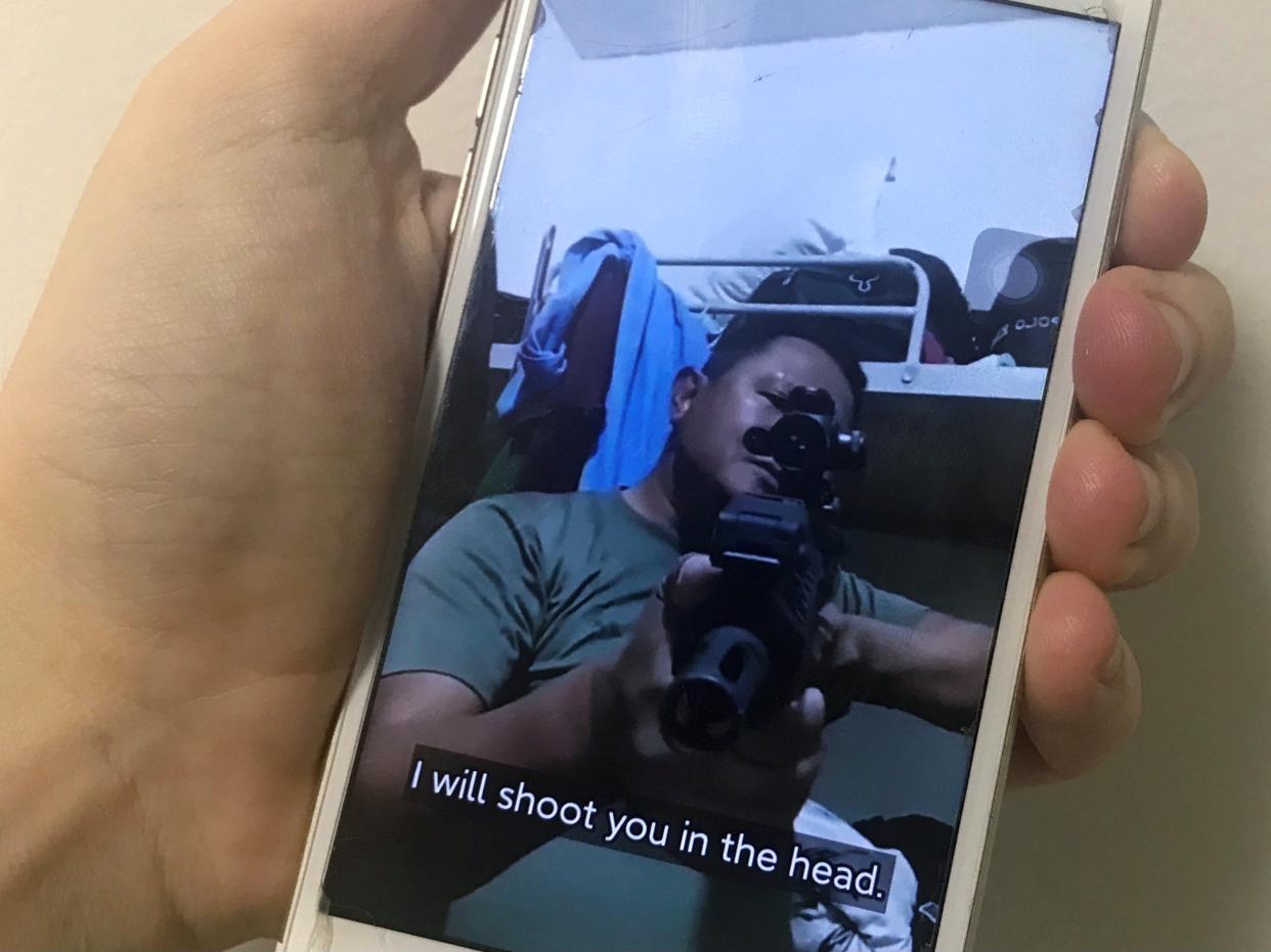 A mobile phone shows a picture of a Myanmar man in an army shirt threatening to shoot anti-coup protesters (REUTERS)