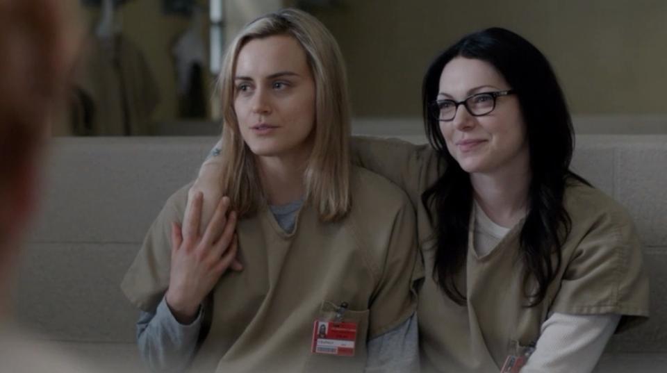 "Orange is the New Black" characters Piper and Alex sitting next to each other in their jail uniforms