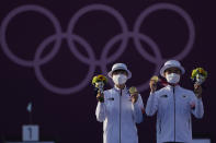 Gold medal winners South Korea's An San, left, and South Korea's Kim Je Deok celebrate on the podium of a mixed team competition at the 2020 Summer Olympics, Saturday, July 24, 2021, in Tokyo, Japan. (AP Photo/Alessandra Tarantino)