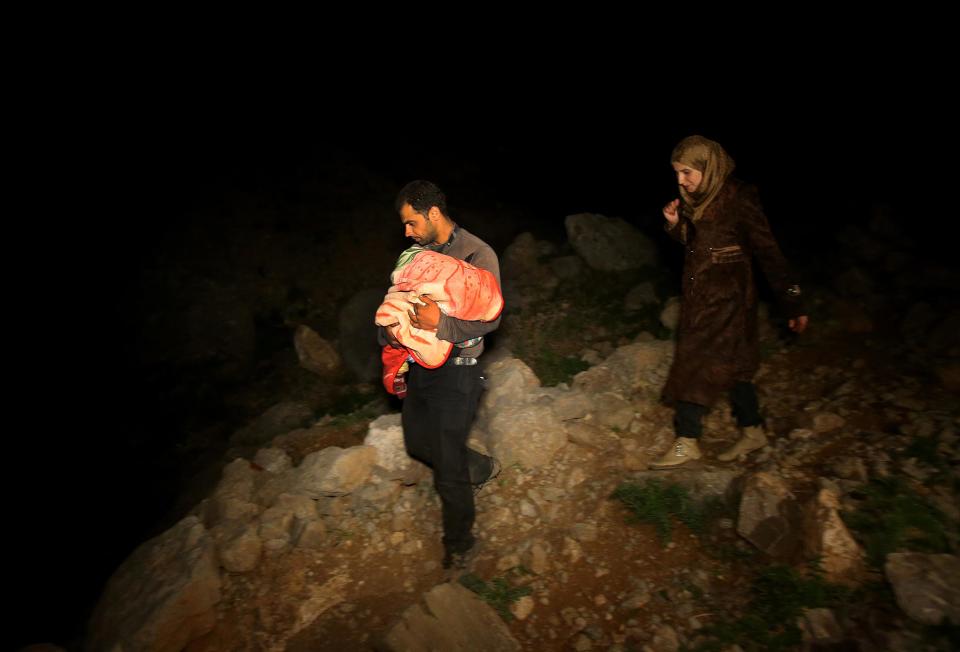 In this picture taken late Saturday April 19, 2014, a Syrian man carries his newborn baby in his arms, left, as he and his wife, right, descend a mountain path from the 2,814-meter (9,232-foot) high Mount Hermon (Jabal el-Sheikh), into the town of Chebaa in southeast Lebanon. Violence forced them to flee their home in the Syrian village of Beit Jinn, near the Israeli-occupied Golan Heights. The group of Syrians that reached Chebaa at sunrise on Sunday joined more than 1 million other Syrian refugees inside Lebanon. (AP Photo/Hussein Malla)