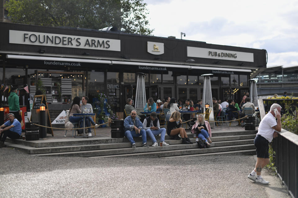 People sit outside a pub on the south bank of river Thames in London, Monday, Aug. 31, 2020. Today is the last day of the 'Eat out to help out' scheme, the UK Government's initiative to support restaurants, cafés, bars and pubs. (AP Photo/Alberto Pezzali)