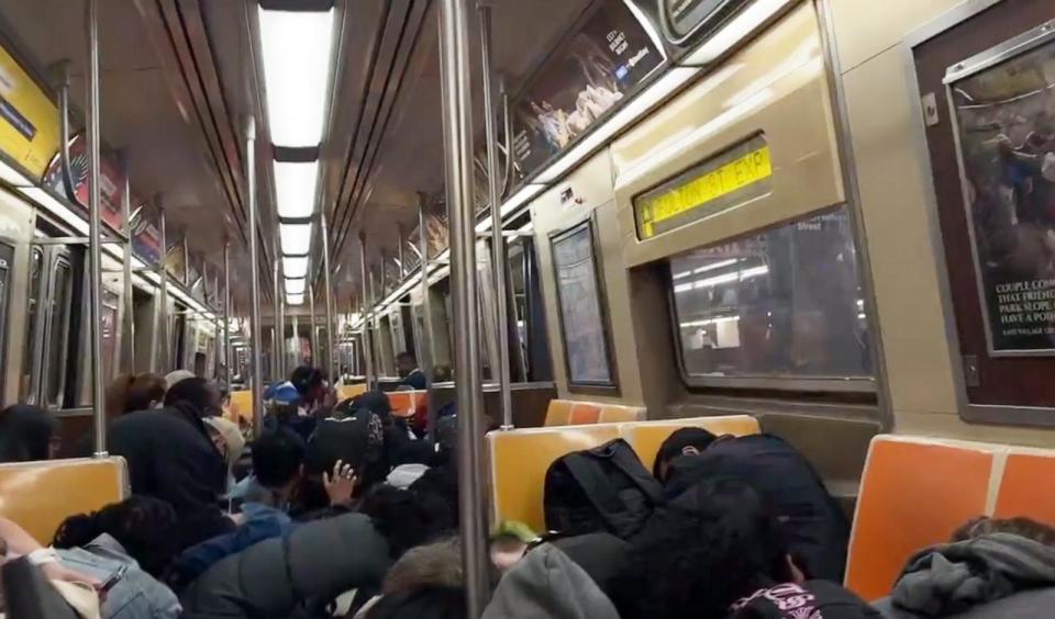 PHOTO: People kneel in a subway car at the scene of a shooting in Brooklyn, New York, on March 14, 2024. (ABC News)