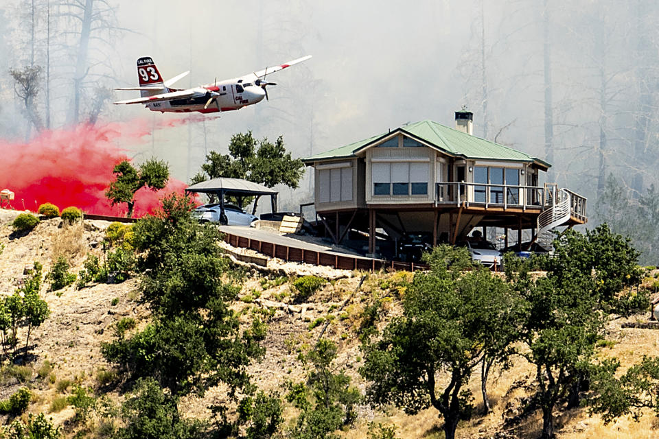 An air tanker drops retardant behind a home while battling the Toll Fire near Calistoga, Calif., on Tuesday, July 2, 2024. An extended heatwave blanketing Northern California has resulted in red flag fire warnings and power shutoffs. (AP Photo/Noah Berger)