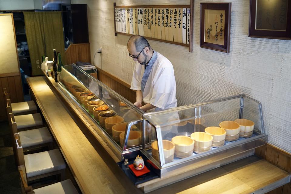 Yosuke Miura makes a rice ball with pieces of grilled salmon at Onigiri Asakusa Yadoroku, Tokyo's oldest onigiri restaurant, on June 3, 2024, in Tokyo. The word "onigiri" just became part of the Oxford English Dictionary this year. The humble sticky-rice ball, a mainstay of Japanese food, has entered the global lexicon. (AP Photo/Eugene Hoshiko)