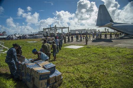 Sailors assigned to the aircraft carrier USS George Washington (CVN 73), marines from the 3d Marine Expeditionary Brigade (3d MEB), and Philippine civilians unload relief supplies that were airlifted ashore in support of Operation Damayan in Guiuan, Philippines November 17, 2013 in this handout photo provided by the U.S. Navy November 18, 2013. REUTERS/Mass Communication Specialist Seaman Beverly Lesonik/U.S. Navy/Handout via Reuters