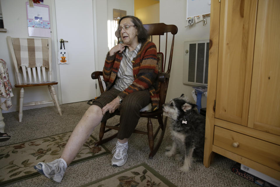 Helen Wagar, who is in her 80s, displays her swollen knee from a fall in a dark stairway during the power blackouts as her dog Pixie looks on at the Villas at Hamilton housing complex for low income seniors Wednesday, Oct. 30, 2019, in Novato, Calif. Wagar fell after stumbling over another woman who had fallen in the stairway. Pacific Gas & Electric officials said they understood the hardships caused by the blackouts but insisted they were necessary. (AP Photo/Eric Risberg)