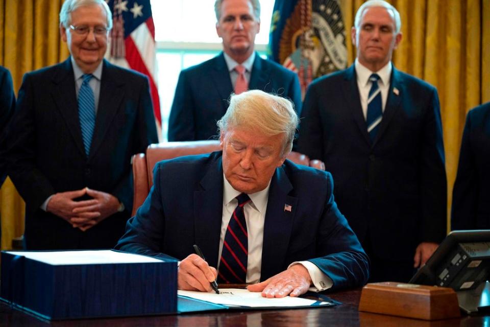President Donald Trump signs a $2 trillion rescue package to provide economic relief on March 27, 2020.
