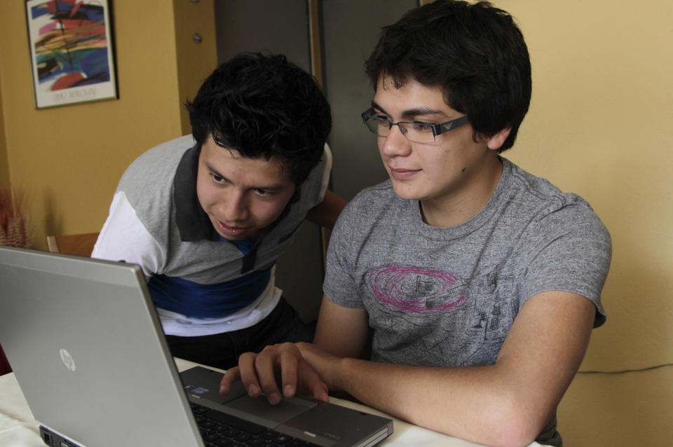 In this photo taken on Tuesday, June 19, students Bryan Polit, left, and Andres Jaramillo use a computer at Jaramillo's home in Quito, Ecuador. Polit and Jaramillo are two of the participants in a new program that aspires to convert this South American nation into a global competitor. In exchange for each state-paid year of school, the professionals guarantee to work at least two years back at home. Ecuador's President Rafael Correa isn't just bent on staunching brain drain, in which top-flight talent flees developing countries for lack of local opportunity. He's determined to reverse it, create a brain gain. (AP Photo/Dolores Ochoa)