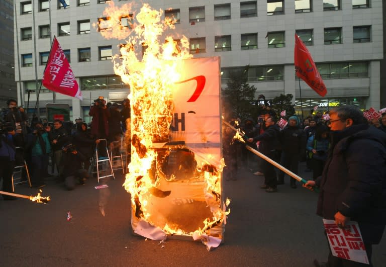 Protesters set fire to a flag with a symbol of the ruling Saenuri Party during a rally urging the impeachment of South Korea's President Park Geun-Hye, in Seoul, on December 7, 2016