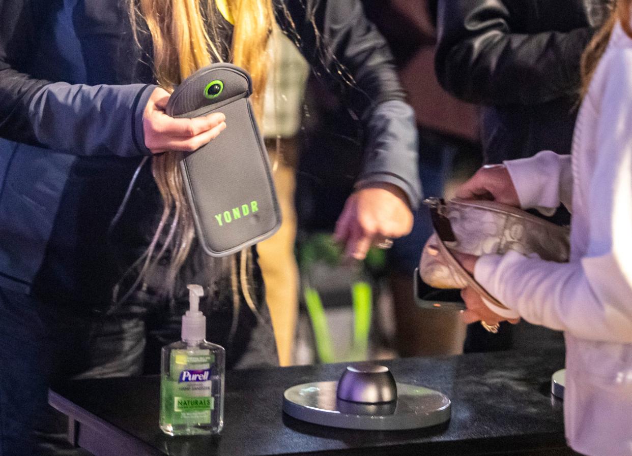 An attendee gets her phone out to place in in a Yondr locking pouch before entering the Chris Rock and Dave Chappelle comedy show at Acrisure Arena in Palm Desert, Calif., Wednesday, Dec. 14, 2022. 