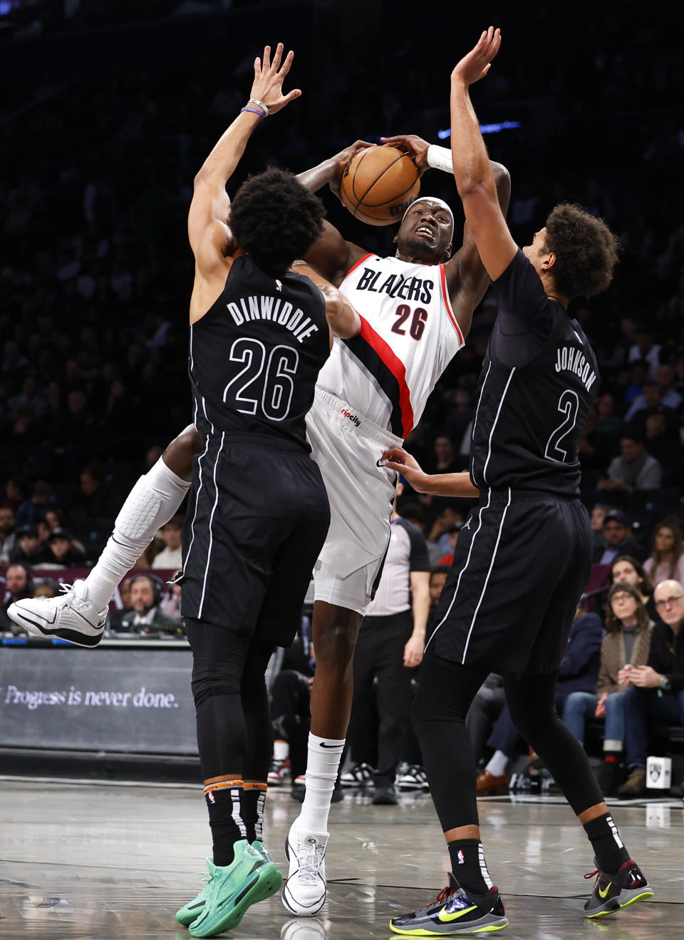 Portland Trail Blazers center Duop Reath, center, drives to the basket against Brooklyn Nets guard Spencer Dinwiddie, left, and forward Cameron Johnson (2) during the first half of an NBA basketball game, Sunday, Jan 7, 2024, in New York. (AP Photo/Noah K. Murray)