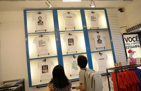 Consumers look at T-shirts with messages about Presidential candidates Jair Bolsonaro and Fernando Haddad at a cloth stamping store in Rio de Janeiro, Brazil October 17, 2018. REUTERS/Ricardo Moraes