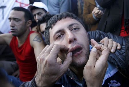 Stranded Iranian migrant has his mouth sewed shut by a colleague during a protest at the Greek-Macedonian border near the Greek village of Idomeni November 26, 2015. REUTERS/Yannis Behrakis