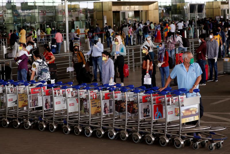 FILE PHOTO: An airport staff member pushes trolleys at Mumbai's airport after the Indian government allowed domestic flight services to resume