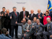 Ukrainian President Petro Poroshenko (3rd L) and others official and workers pose for a picture after a ceremony to unveil the 'New Safe Confinement' (NSC) arch, that will block radiation from the damaged reactor at the Chernobyl nuclear power plant, Ukraine, November 29, 2016. REUTERS/Gleb Garanich