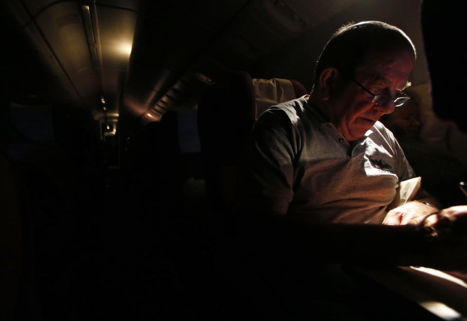 A passenger, John Gardner of Australia, focuses on his Sudoku puzzle, as other passengers sleep onboard Malaysia Airlines Boeing 777-200ER flight MH318 as it cruises towards Beijing