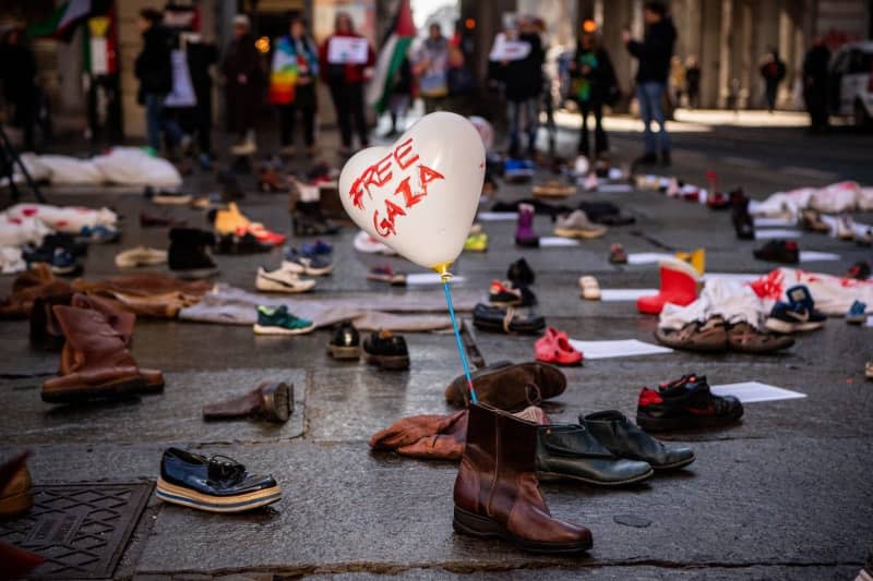 People holding posters for ceasefire stand next to the ground shoes to represent the victims during a march at Turin City Hall in support of palestine and calling for an end to the war in Gaza. Marco Alpozzi/LaPresse via ZUMA Press/dpa