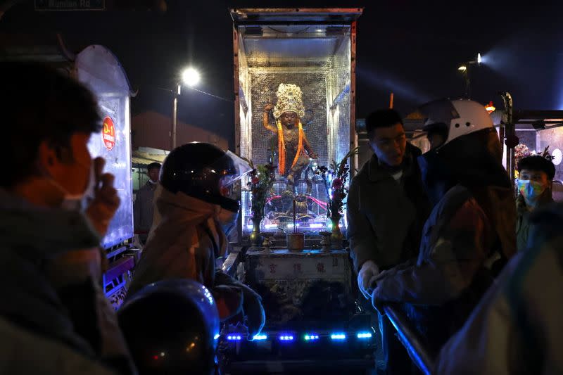 Participants wearing motorcycle helmets while carrying a god statue take a break from getting sprayed with firecrackers, during the 'Beehive Firecrackers' festival at the Yanshui district in Tainan