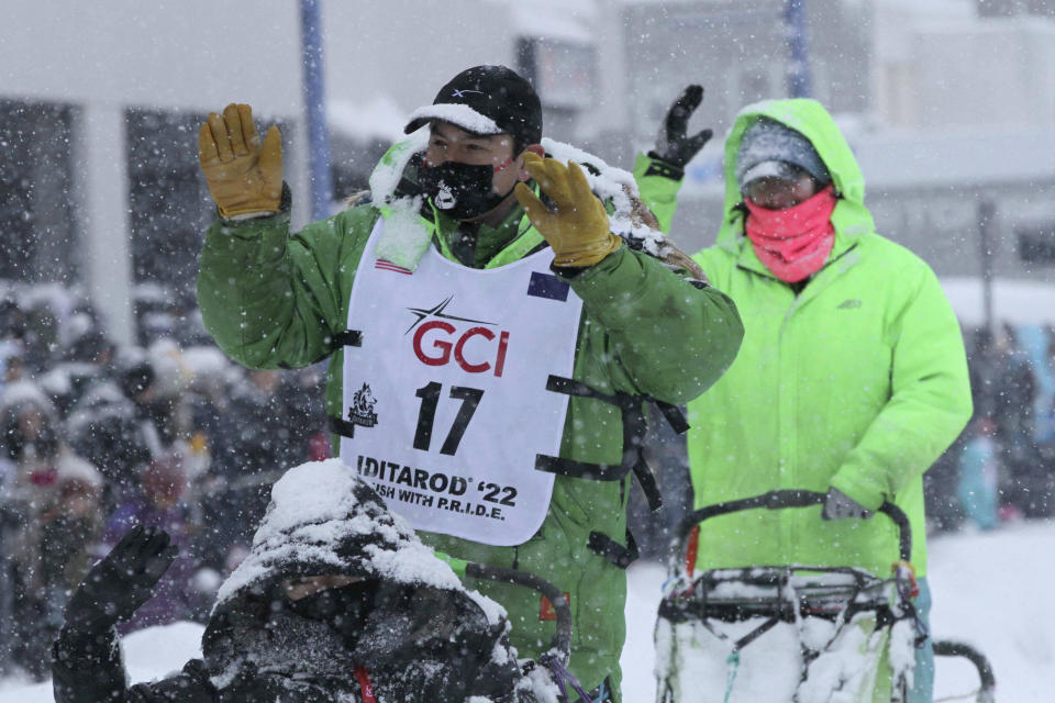 FILE - Ryan Redington, a musher from Wasilla, Alaska, and grandson of one of the race founders, Joe Redington Sr., greets fans while taking his sled dogs through a snowstorm in downtown Anchorage, Alaska, on March 5, 2022, during the ceremonial start of the Iditarod Trail Sled Dog Race. The winner of the Iditarod Trail Sled Dog Race pockets only about $50,000, but the real prize is a bronze statue of race co-founder Joe Redington Sr. embracing a sled dog under the iconic burled arch finish line. Ever since the first grueling Iditarod race across the Alaska wilderness, mushers with the last name Redington have lined up 71 times to win that trophy. (AP Photo/Mark Thiessen, File)