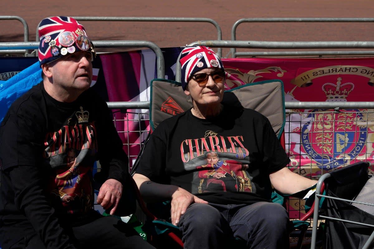 Royal fans John Loughrey, left and Sky London sit at a fence barricade near Buckingham Palace (AP)