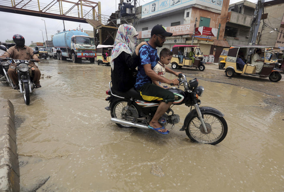 Motorcyclists drive through a road flooded by heavy rainfall in Karachi, Pakistan, Sunday, Aug. 9, 2020. Three days of heavy monsoon rains triggering flash floods killed at least dozens people in various parts of Pakistan, as troops with boats rushed to a flood-affected district in the country's southern Sindh province Sunday to evacuate people to safer places. (AP Photo/Fareed Khan)