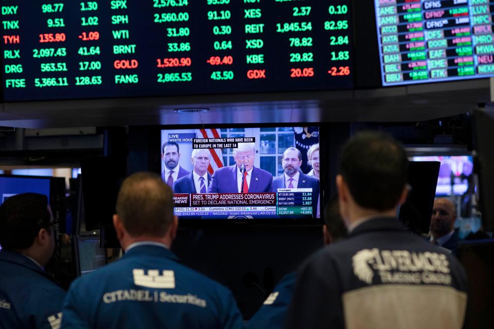 Traders listen at the New York Stock Exchange to President Donald Trump's televised speech from the White House, Friday, March 13, 2020, in New York.