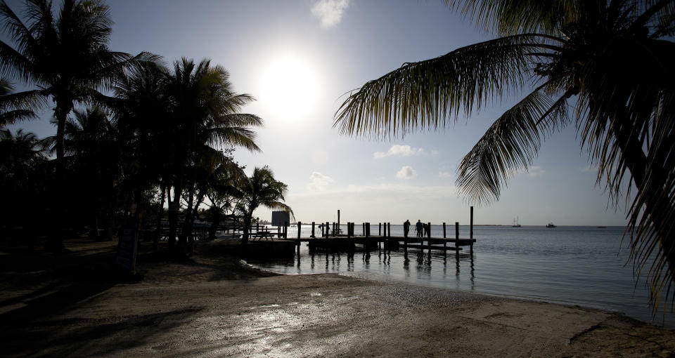 In this Feb. 12, 2013 photo,visitors to Key Largo, Fla., stand on a pier and watch the sunset. If you're heading south into the Keys from the Miami or Fort Lauderdale areas, Key Largo is the first island you hit. State parks offer great opportunities for birdwatching and nature photography. (AP Photo/J Pat Carter)