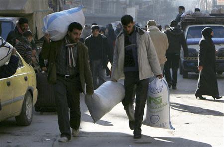 Men walk as they carry bags at the Karaj al-Hajez crossing, a passageway separating Aleppo's Bustan al-Qasr, which is under the rebels' control and Al-Masharqa neighbourhood, an area controlled by the regime February 9, 2014. REUTERS/Hosam Katan